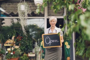 GettyImages 477952776 300x200 - Smiling mature woman holding open sign at flower shop.